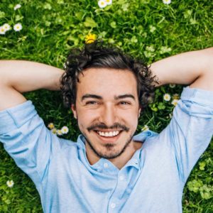 man smiling and laying in the grass