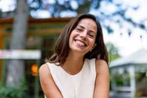 A young lady is seated outdoors, flaunting her smile after a fluoride treatment in Pittsburgh, PA