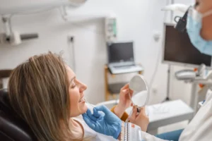 Patient holding a mirror during a dental consultation for a smile makeover in a clinic in Pittsburgh, PA