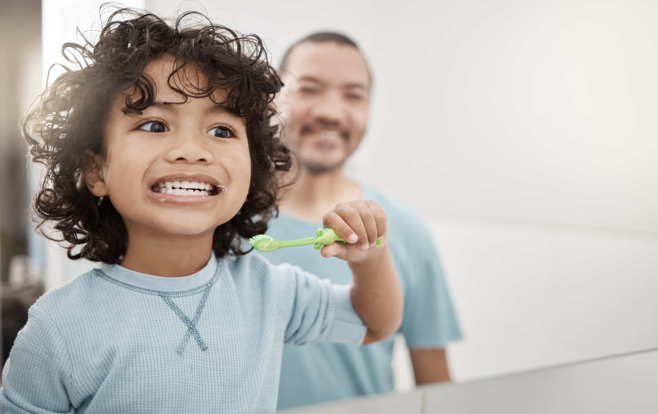 Parent guiding child brushing teeth to support kids oral health in Pittsburgh, PA Metro Area